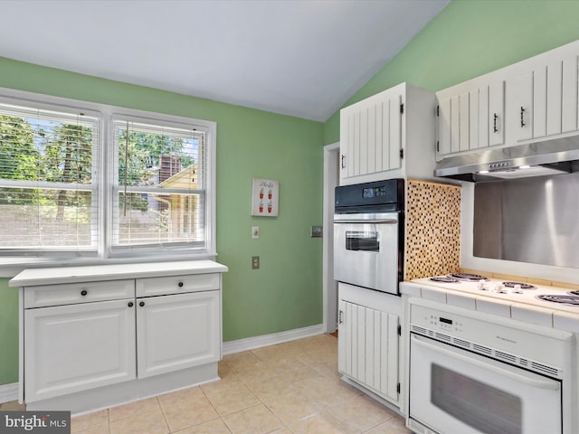 kitchen featuring under cabinet range hood, stove, white cabinets, and oven