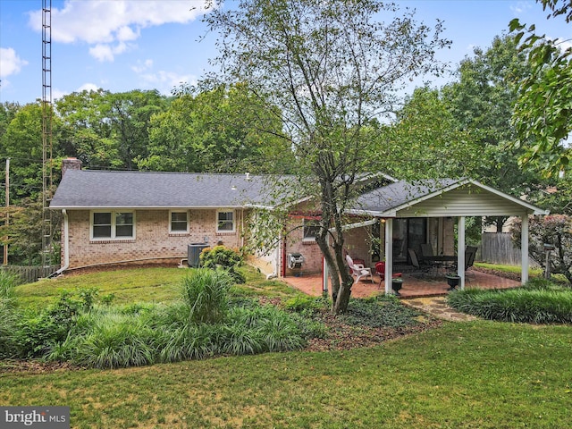 view of front of house with fence, a patio area, a front lawn, central AC, and brick siding