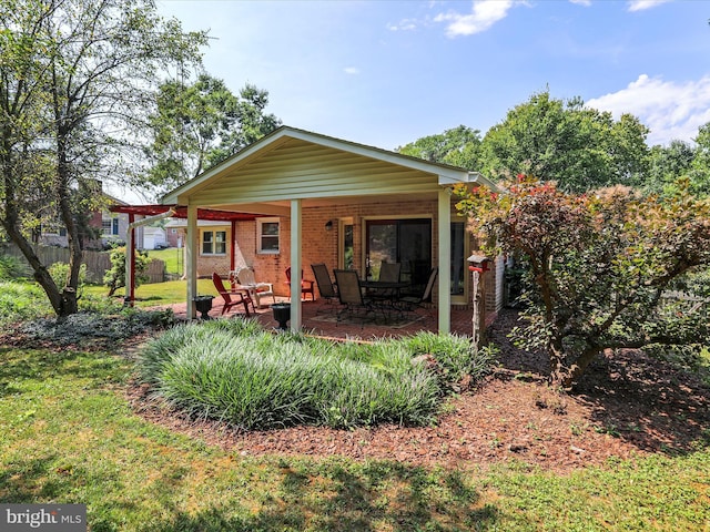 back of house featuring a yard, brick siding, fence, and a patio