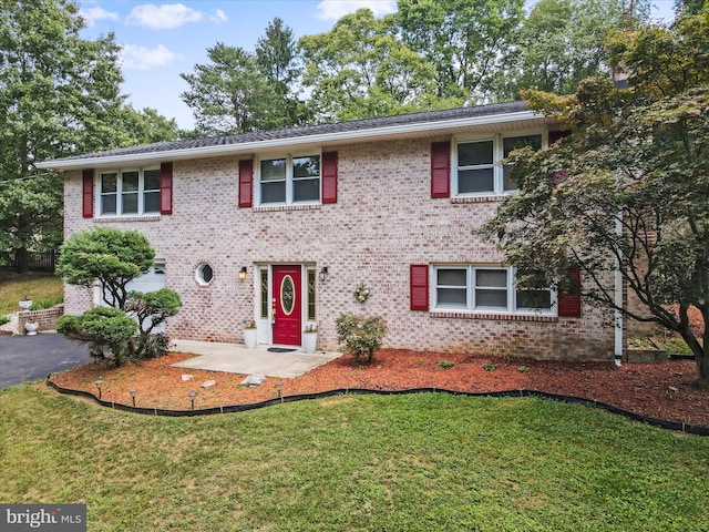 view of front facade with brick siding, driveway, and a front lawn