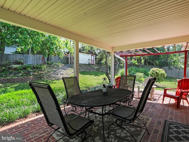 view of patio / terrace featuring an outbuilding, a shed, outdoor dining area, and a fenced backyard