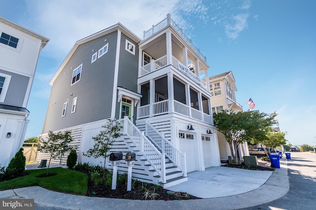 view of front facade featuring an attached garage, a sunroom, stairs, and concrete driveway