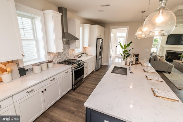 kitchen with decorative backsplash, dark wood-type flooring, wall chimney exhaust hood, white cabinetry, and stainless steel appliances