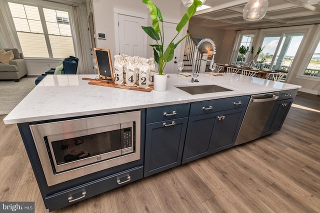 kitchen featuring coffered ceiling, beam ceiling, appliances with stainless steel finishes, hardwood / wood-style flooring, and sink