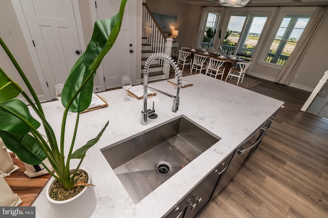 room details featuring light stone counters, a sink, dark wood finished floors, and baseboards