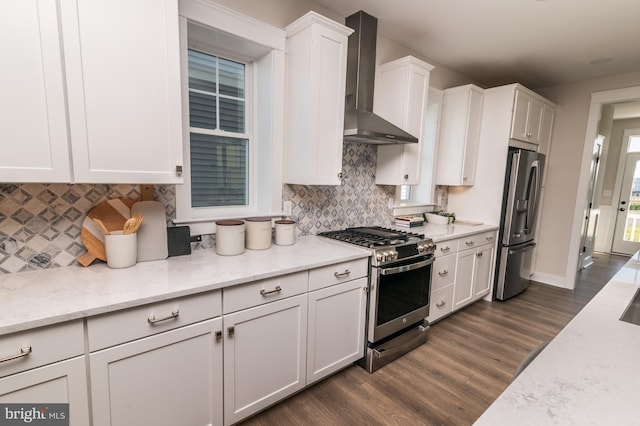 kitchen featuring light stone counters, stainless steel appliances, white cabinets, dark wood-style floors, and wall chimney exhaust hood