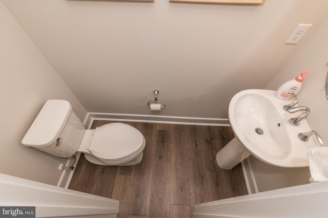 bathroom with a sink, toilet, baseboards, and wood finished floors