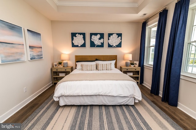 bedroom featuring a raised ceiling, dark wood finished floors, and baseboards