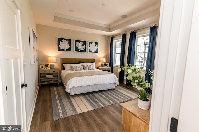 bedroom with dark wood-style floors, baseboards, a tray ceiling, and ornamental molding