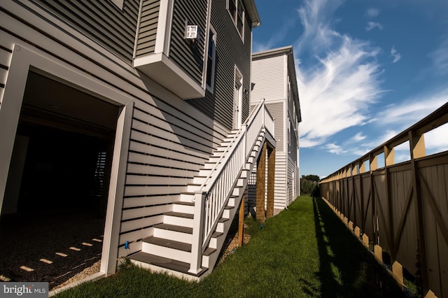 view of home's exterior with stairs, a lawn, and fence