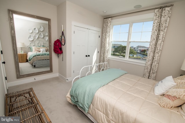 carpeted bedroom featuring baseboards and a closet