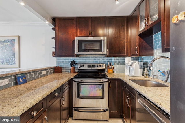 kitchen featuring appliances with stainless steel finishes, a sink, light stone counters, and decorative backsplash