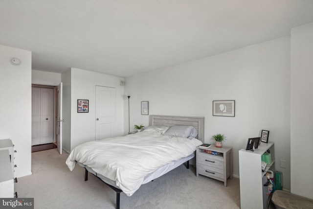 bedroom with a closet, light colored carpet, and baseboards