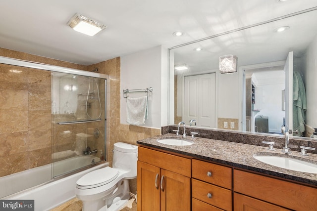 full bathroom with enclosed tub / shower combo, toilet, and vanity