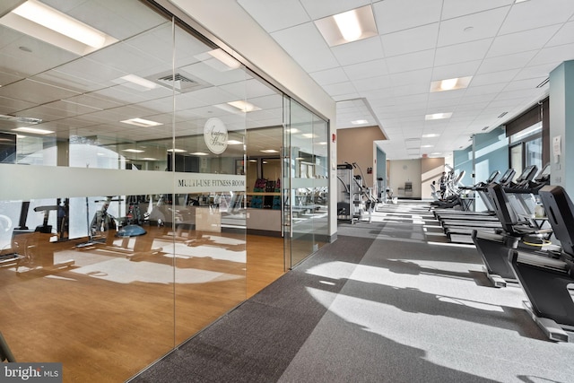 gym featuring hardwood / wood-style flooring and a drop ceiling