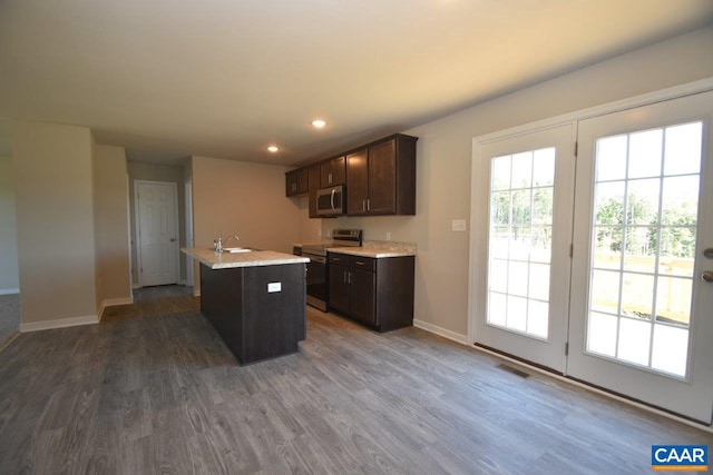 kitchen featuring dark brown cabinetry, an island with sink, hardwood / wood-style flooring, sink, and range with electric stovetop