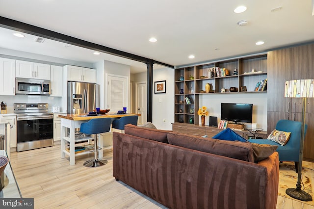 living area with beamed ceiling, recessed lighting, visible vents, and light wood-style floors