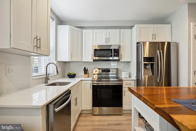 kitchen featuring stainless steel appliances, sink, white cabinets, and light hardwood / wood-style floors