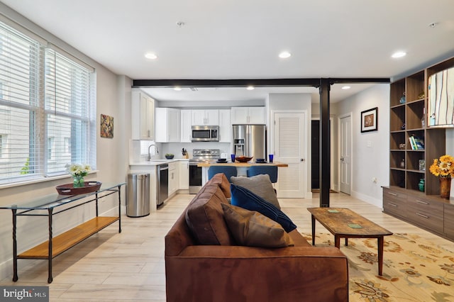 living area featuring beamed ceiling, light wood-type flooring, and recessed lighting