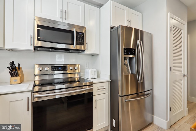 kitchen featuring light wood-type flooring, appliances with stainless steel finishes, and white cabinetry