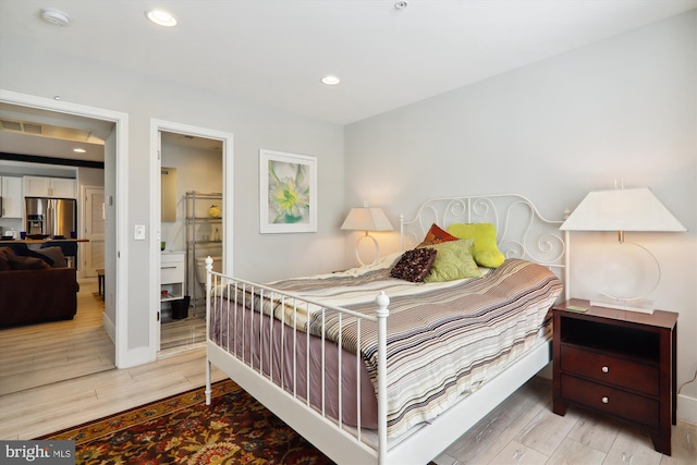 bedroom with light hardwood / wood-style flooring, stainless steel fridge, and ensuite bathroom