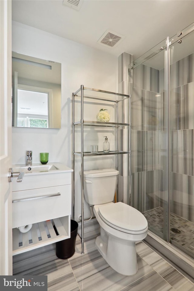 bathroom with toilet, vanity, a shower stall, and visible vents