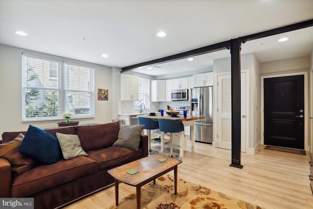 living room featuring plenty of natural light, sink, and light hardwood / wood-style floors