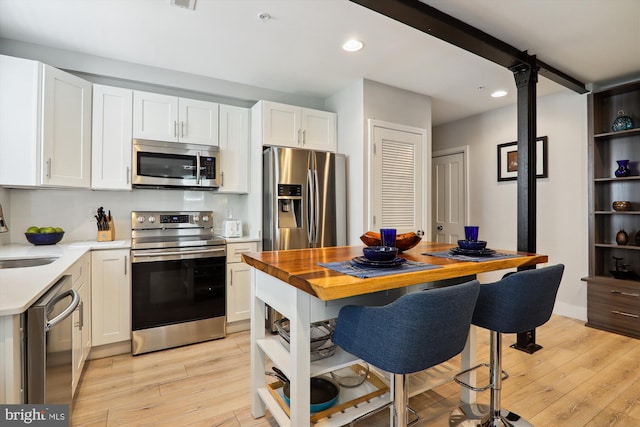 kitchen with stainless steel appliances, light hardwood / wood-style floors, white cabinetry, and sink