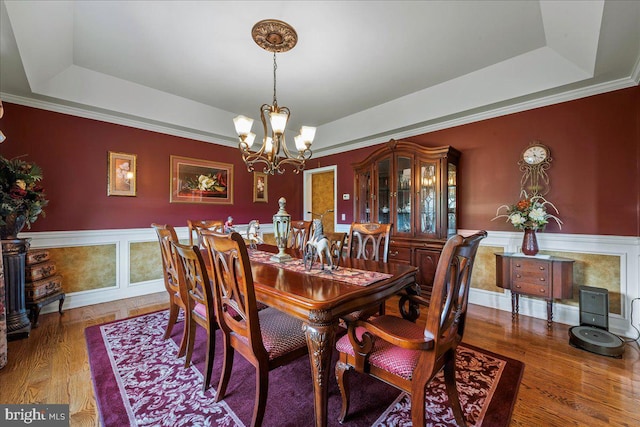 dining room with hardwood / wood-style flooring, crown molding, a notable chandelier, and a tray ceiling