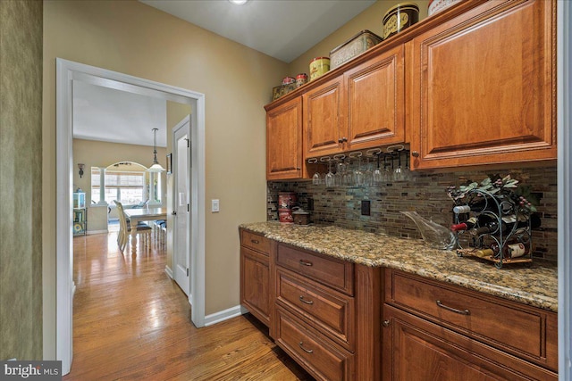 kitchen with light wood-type flooring, tasteful backsplash, and light stone countertops