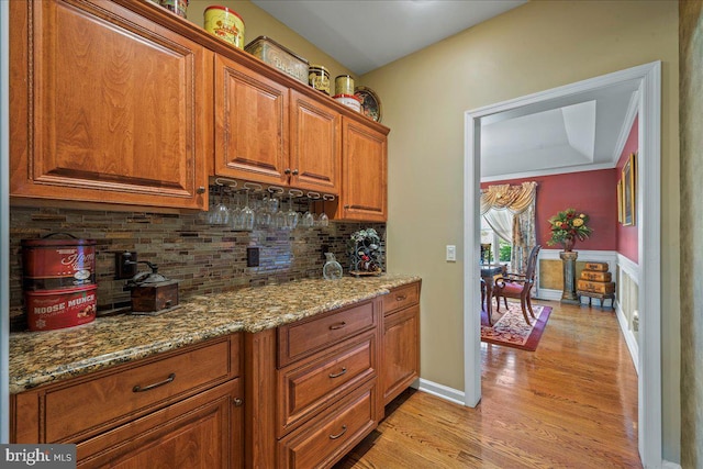 kitchen featuring light stone counters, ornamental molding, light wood-type flooring, and tasteful backsplash