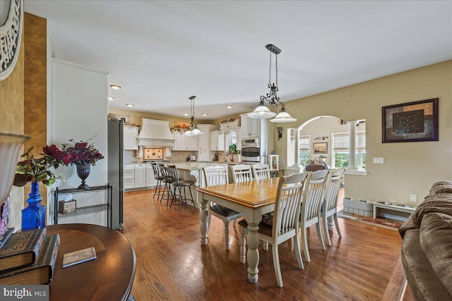 dining room featuring an inviting chandelier, decorative columns, and hardwood / wood-style flooring