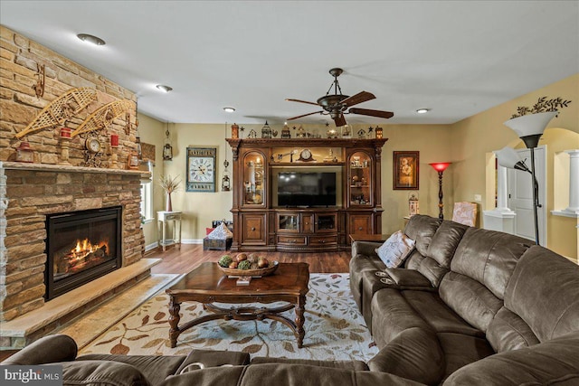 living room with hardwood / wood-style floors, ceiling fan, and a fireplace