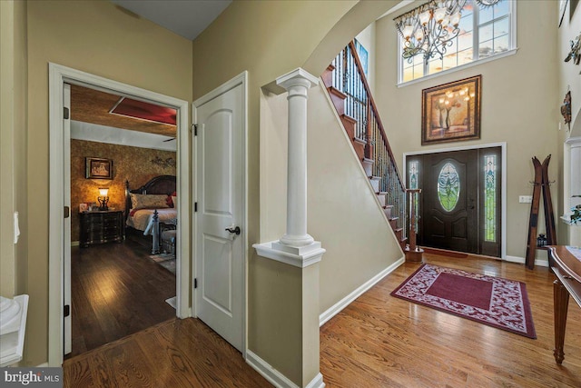 entryway featuring a towering ceiling, hardwood / wood-style flooring, and decorative columns