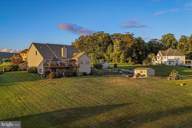 yard at dusk featuring a deck and a storage shed