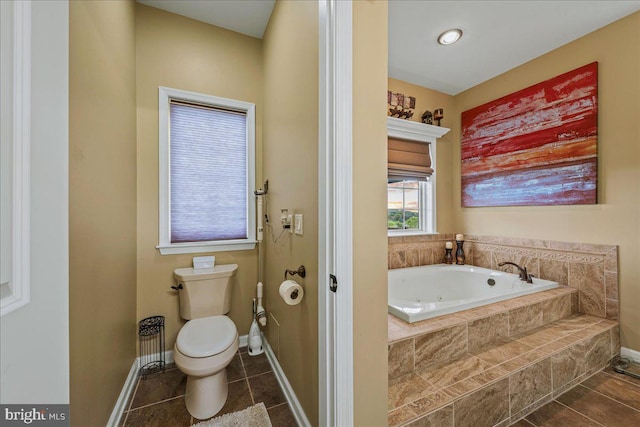 bathroom featuring tiled tub, tile patterned flooring, and toilet