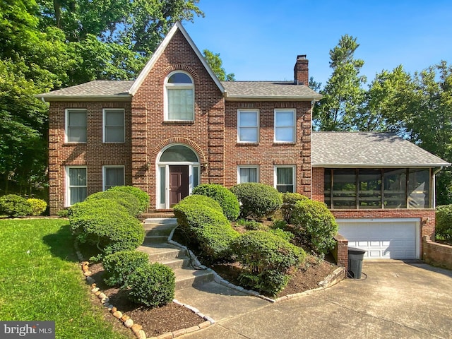 colonial inspired home featuring driveway, brick siding, and a chimney