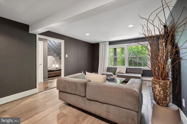 living room featuring beam ceiling, light hardwood / wood-style flooring, and a baseboard heating unit