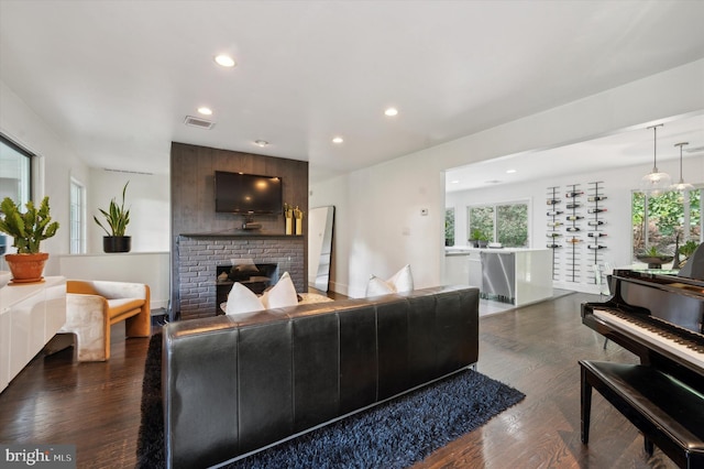 living room with dark wood-type flooring and a brick fireplace