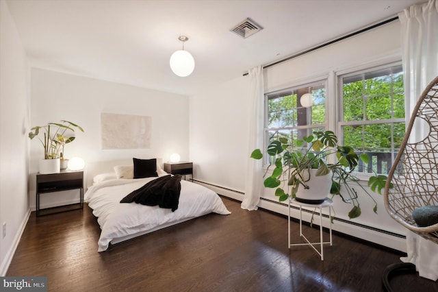 bedroom with a baseboard heating unit and dark wood-type flooring