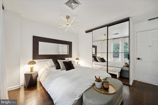 bedroom featuring dark wood-type flooring, a closet, and a chandelier