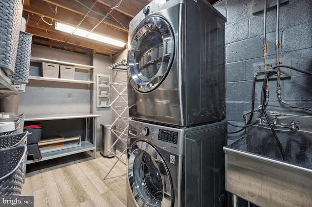 clothes washing area with light wood-type flooring and stacked washing maching and dryer