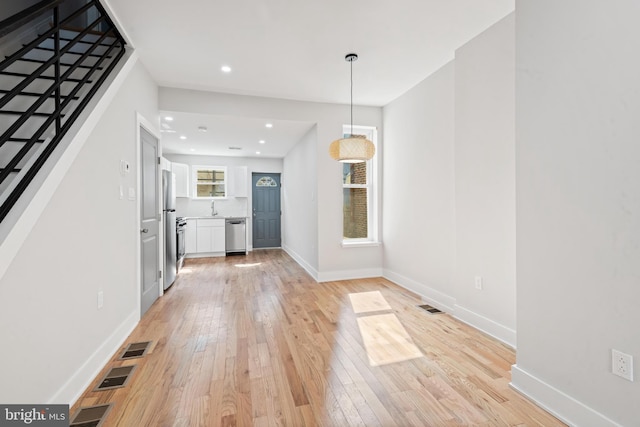 unfurnished living room with light hardwood / wood-style floors and sink