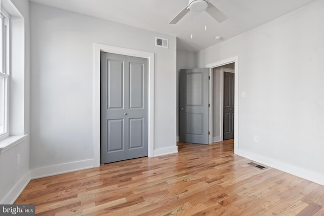 unfurnished bedroom featuring light wood-type flooring, ceiling fan, and a closet