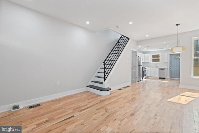 unfurnished living room with light wood-type flooring and sink