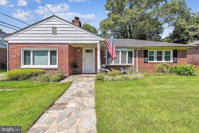 view of front of home featuring a front yard, brick siding, and a chimney