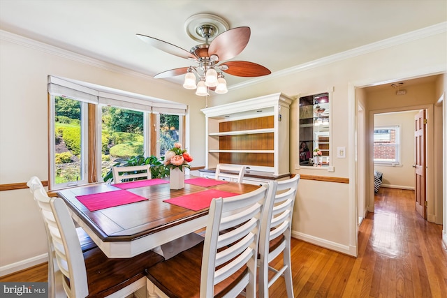 dining area featuring light wood-style flooring, baseboards, ceiling fan, and crown molding