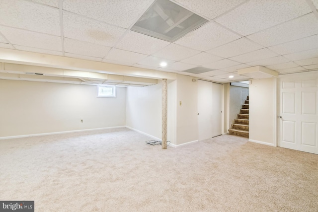 below grade area featuring a drop ceiling, carpet floors, visible vents, baseboards, and stairway