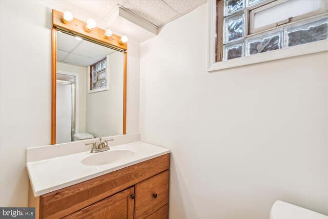 bathroom with plenty of natural light, vanity, a paneled ceiling, and toilet