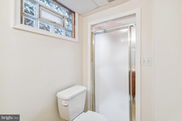 bathroom with a paneled ceiling, toilet, and walk in shower